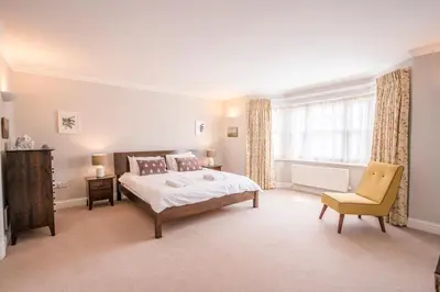 a bedroom with a bed and a chair and a window at Cherry Tree House, Aldeburgh in Aldeburgh