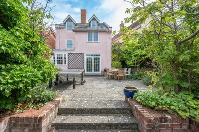 a patio in front of a pink house at Cherry Tree House, Aldeburgh in Aldeburgh