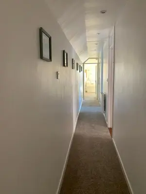 a hallway with white walls and a long hallway at The Coach House, Framsden