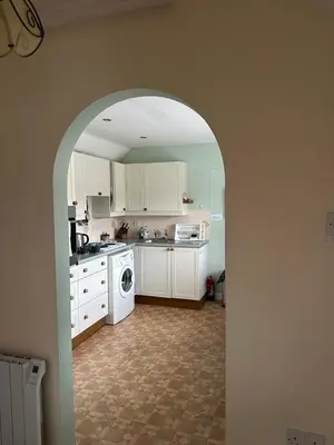 a kitchen with white cabinets and a washer and dryer at Little Furrows, Wenhaston in Wenhaston
