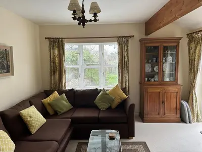 a living room with a brown couch and a window at Little Furrows, Wenhaston in Wenhaston