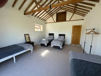 a room with three beds and a wooden ceiling at Sleeps18 character barns in Old Hurst