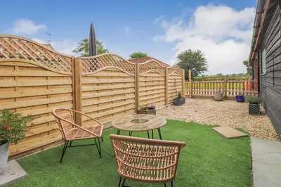 a patio with a table and chairs and a fence at Gorgeous rural dog welcoming Milk Churn - Suffolk in Eye