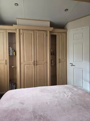 a bedroom with a bed and some cupboards at Sunny corner caravan in Saint Osyth