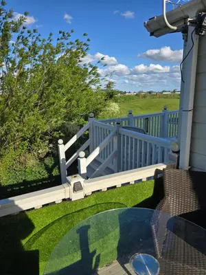 a porch with a fence and a glass table at Sunny corner caravan in Saint Osyth