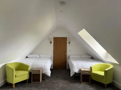 a attic room with two beds and a chair at The Lodge in Newbourn