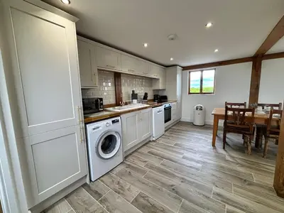 a kitchen with a washer and dryer and a table at The Lodge in Newbourn