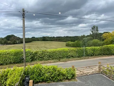 a view of a road with a fence and a field at The Lodge in Newbourn