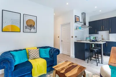 a living room with a blue couch and a kitchen at Central Studio Flats with Parking in Southend on Sea in Southend-on-Sea