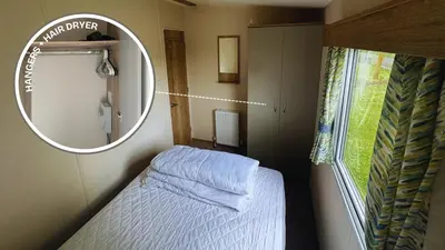 a small bedroom with a bed and a mirror at Sunny Beach Holidays Home in Jaywick Sands