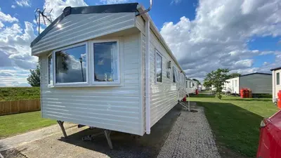 a tiny house on a trailer in a yard at Sunny Beach Holidays Home in Jaywick Sands