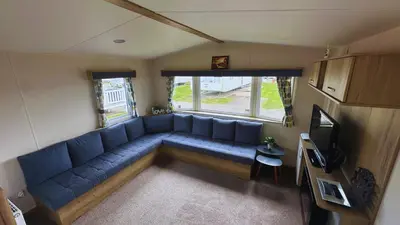 a living room with a blue couch and a tv at Sunny Beach Holidays Home in Jaywick Sands