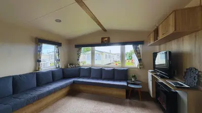a living room with a blue couch and a tv at Sunny Beach Holidays Home in Jaywick Sands