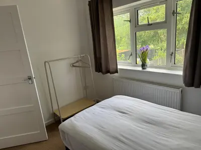 a bedroom with a bed and a window with a vase of flowers at 3 bedrooms house in Stevenage
