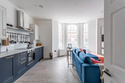 a kitchen with a blue couch and a kitchen with windows at 2BR Apartments in Southend near City Centre in Southend-on-Sea