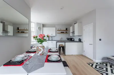 a white kitchen with a table with plates on it at 2BR Apartments in Southend near City Centre in Southend-on-Sea