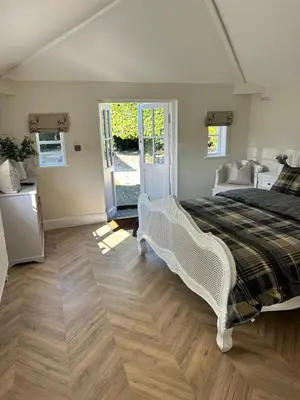 a bedroom with a large white bed and wooden floors at Historic Retreat Near To Mersea Island in Peldon