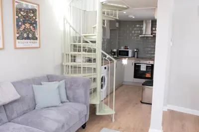 a living room with a gray couch and a kitchen at Horseshoe house in Sudbury