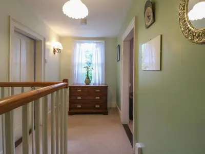 a hallway with a staircase with a dresser and a window at Curry Farm in Southminster