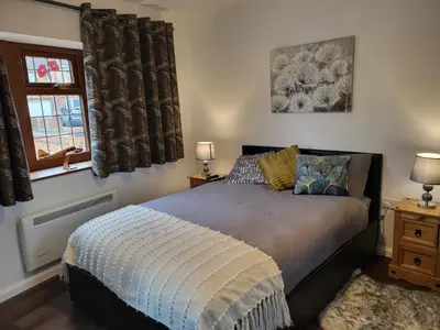 a bedroom with a bed and two windows with curtains at Cozy Studio Newly Furnished in Colchester