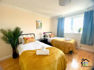 two beds in a room with blue curtains at CB Stays - 2 Bedroom & 2 Toilet Flat - Near Mills Road and Train Station with Parking in Cambridge