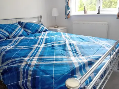 a bed with a blue and white blanket and pillows at 'Ks' Yard in Great Dunmow