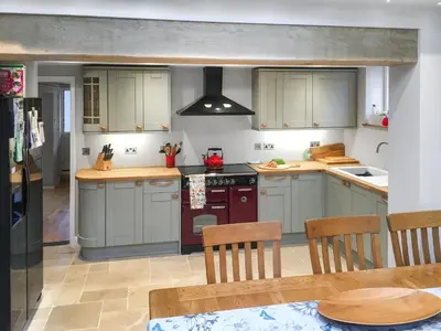 a kitchen with gray cabinets and a red stove top oven at Hill House in Snape