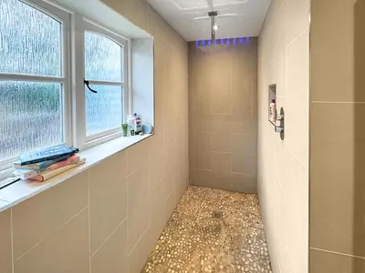 a bathroom with a walk in shower next to a window at Hill House in Snape