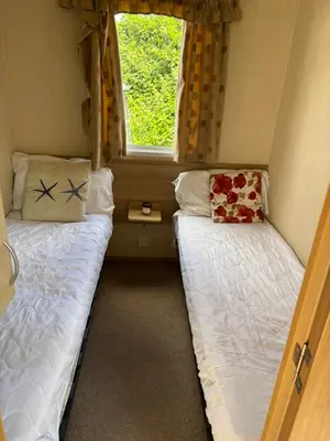 two beds in a small room with a window at Singh&Leite Family RF10 in Jaywick Sands