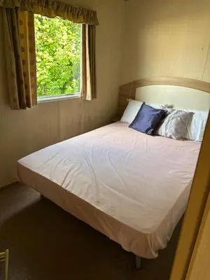 a bedroom with a large white bed with a window at Singh&Leite Family RF10 in Jaywick Sands