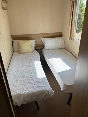 two twin beds in a small room with a window at Singh&Leite Family RF10 in Jaywick Sands