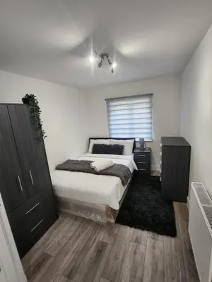 a bedroom with a bed and a dresser and a window at Ensuite deluxe home in Basildon