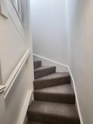 a stairway with brown carpeted stairs in a house at Ensuite deluxe home in Basildon