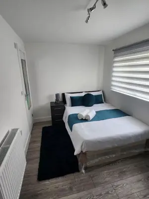 a bedroom with a bed with blue pillows and a window at Ensuite deluxe home in Basildon