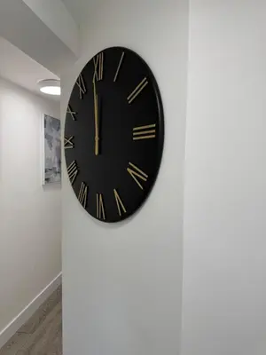 a black clock hanging on a wall at Ensuite deluxe home in Basildon