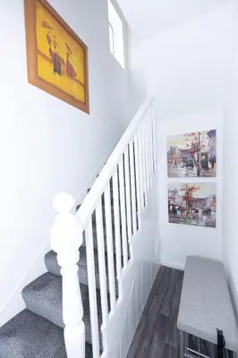 a white staircase with a picture on the wall at Urban Escape - Flat in Brandon