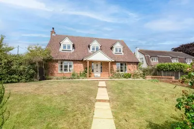 a brick house with a lawn in front of it at Hollybank Cottage, Ufford in Ufford