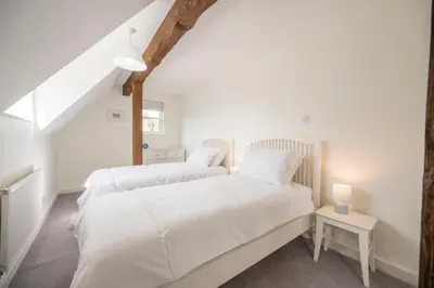 two beds in a room with white walls at Hollybank Cottage, Ufford in Ufford
