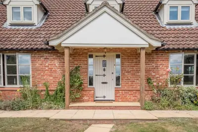 a red brick house with a white door at Hollybank Cottage, Ufford in Ufford