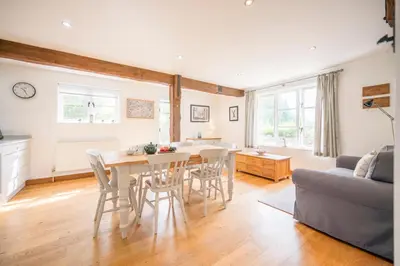 a kitchen and living room with a table and chairs at Hollybank Cottage, Ufford in Ufford