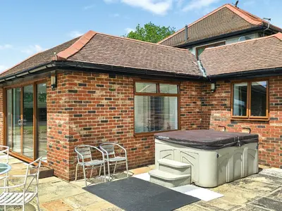 a brick house with a patio with a grill and chairs at Belt Annexe in Writtle