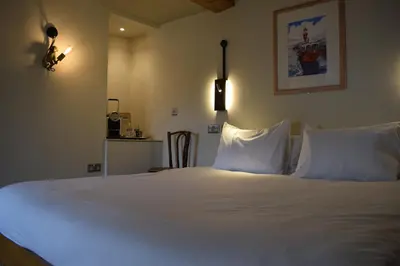 a bedroom with a bed with white sheets and pillows at Alma Inn & Dining Rooms in Harwich