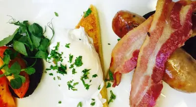 a plate of breakfast food with bacon eggs and vegetables at Alma Inn & Dining Rooms in Harwich