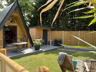 a small cabin with a deck in a backyard at Sycamore Lodge with Hot Tub- Quirky & Romantic in Halstead