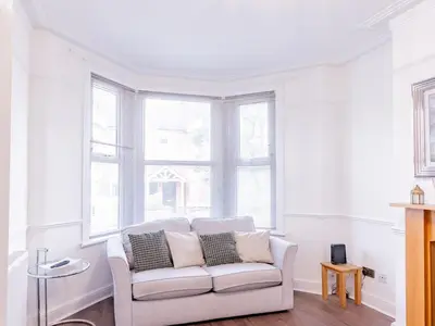 a living room with a white couch in front of a window at Pass the Keys Comfortable Flat with Patio Sleeps 4 in Westcliff On Sea
