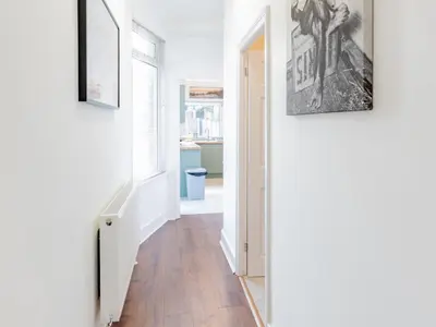 a hallway with white walls and wood floors and two framed pictures at Pass the Keys Comfortable Flat with Patio Sleeps 4 in Westcliff On Sea