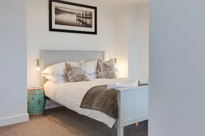 a bedroom with a white bed with a night stand at Studio Lodge with parking - Stansted airport in Hatfield Broad Oak