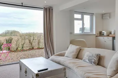 a living room with a couch and a large window at Studio Lodge with parking - Stansted airport in Hatfield Broad Oak
