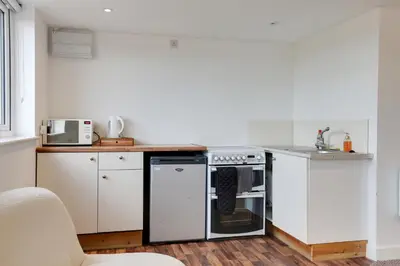 a kitchen with white cabinets and a stove top oven at Studio Lodge with parking - Stansted airport in Hatfield Broad Oak