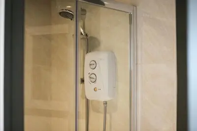 a shower with a white soap dispenser in a shower stall at Studio Lodge with parking - Stansted airport in Hatfield Broad Oak